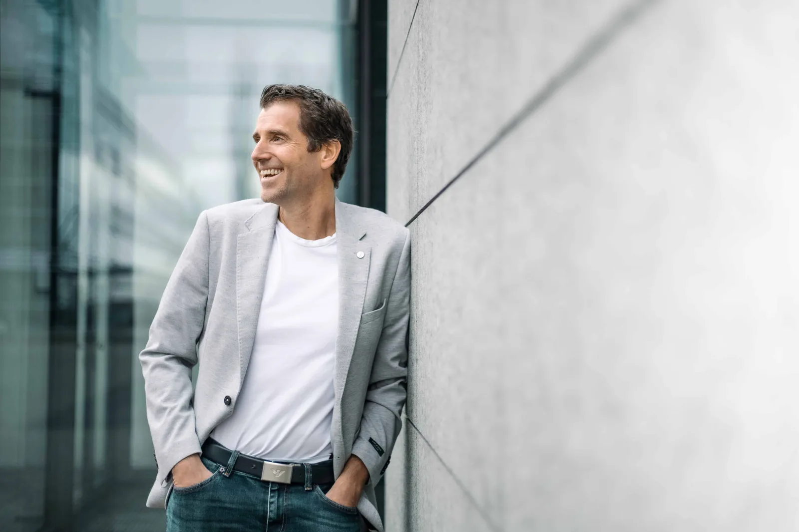Claus-Stefan Duffner in grauem Blazer an Betonwand lehnend