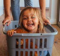 Kind im Wäschekorb, spielerischer friedvoller Familienalltag
