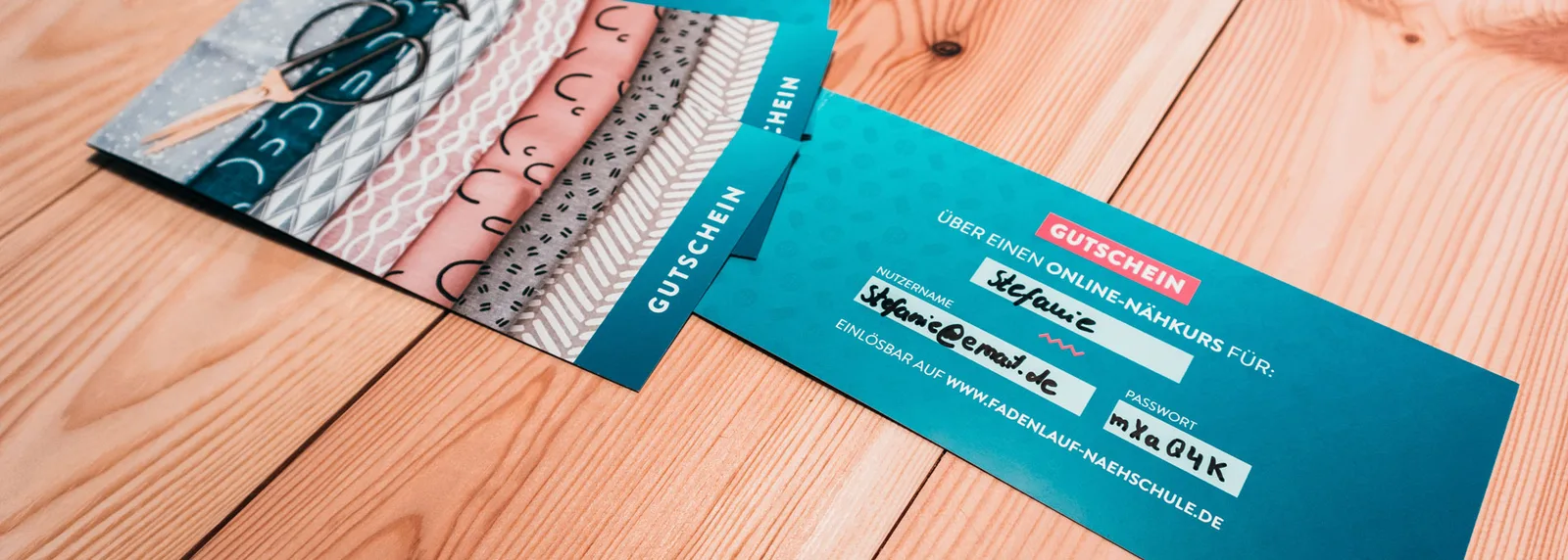 Gutschein für Online-Nähkurs auf Holztisch mit Stoffen, Text und Passwort sichtbar