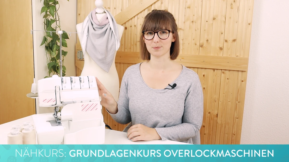 Frau mit Brille vor Overlockmaschine und Nähprojekten, Grundlagenkurs für Anfänger