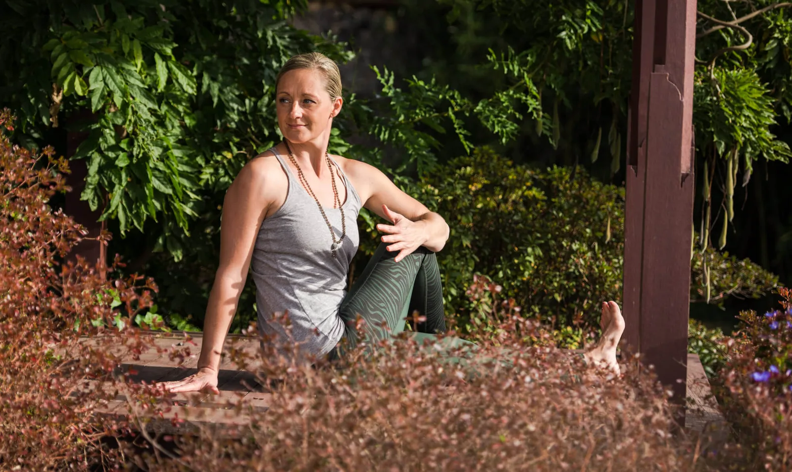 Doreen Böhme in Yogaposition vor grünem Garten im Freien
