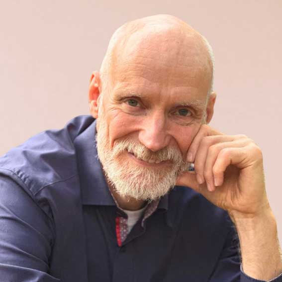 Porträtfoto von Frank-Robert Belewsky, älterer männlicher Speaker mit weißem Bart in dunklem Hemd, nachdenkliche Pose
