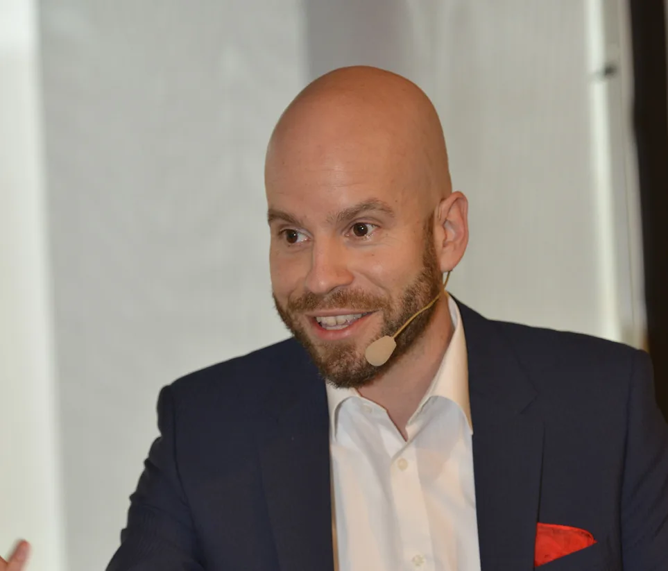Tim Taxis mit Headset und rotem Tuch, lächelnd, Business-Anzug dunkelblau