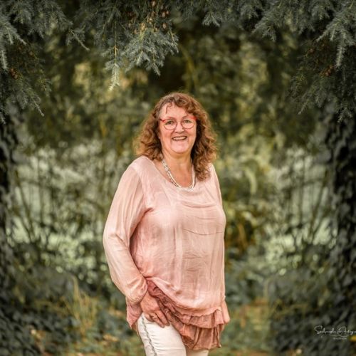 Herzenstiere und Silvester Kongresspaket Premium – Tierangst-Kurs 9 Monika Rekelhof, Frau mit lockigen Haaren und Brille vor Nadelbaum-Allee