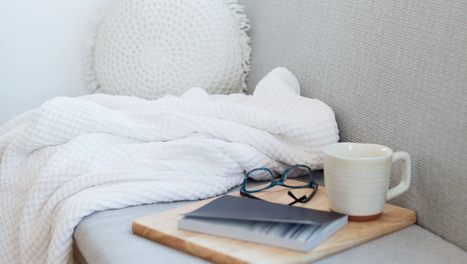 Cozy Arbeitsplatz mit weißer Decke, Kissen, Notebook und Tasse Tee