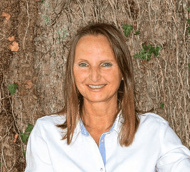 Elvira Littner, Mentorin, vor Baumrinden-Hintergrund in weißer Bluse