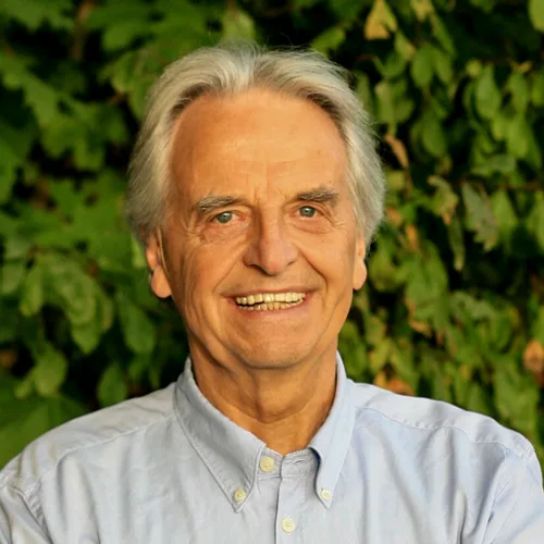 Porträtfoto von Clemens Kuby in dunklem Hemd vor Bürogebäude-Hintergrund