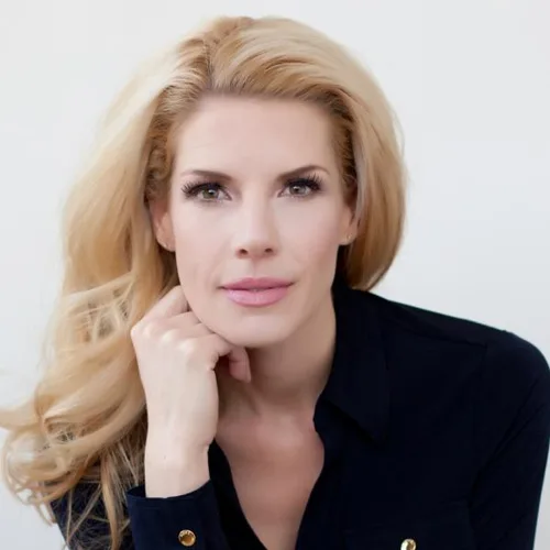 Porträtfoto von Dr. Joy Martina mit blonde Haaren, lächelnd, Hand am Kinn