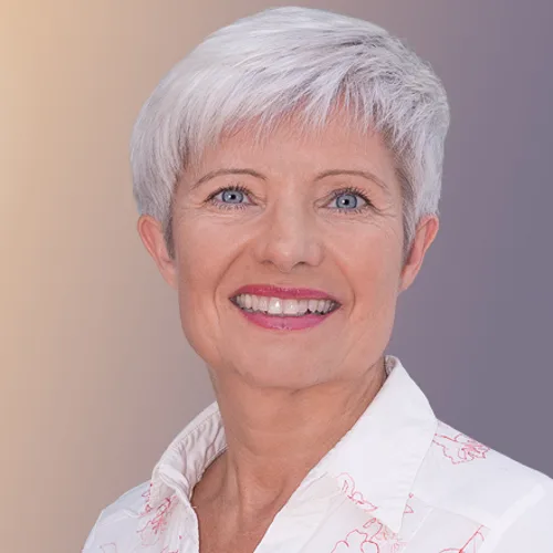 Martina Haller, blonde Frau lächelt vor farbigem Hintergrund