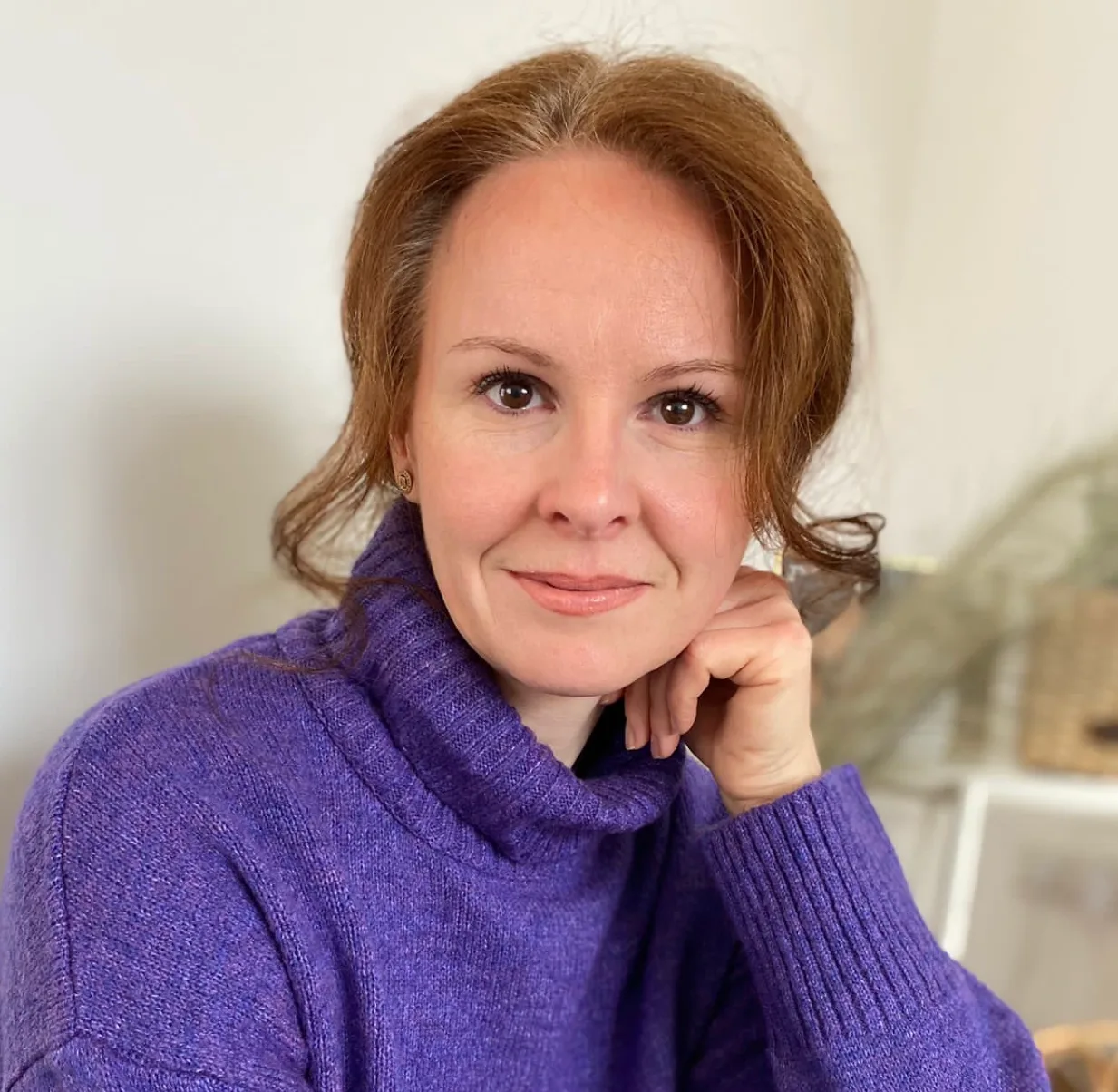 Porträt einer Frau mit rötlich-braunem Haar in violettem Rollkragenpullover
