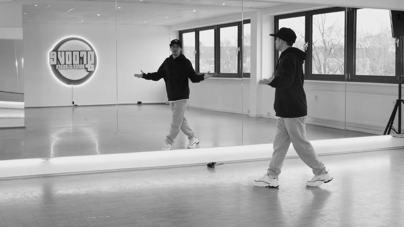 Hip Hop Basics – Hip-Hop-Tanzkurs per Video 6 Zwei Tänzer in modernem Tanzstudio mit großem Spiegel, Groove Dance Academy Logo sichtbar, Choreografie-Anleitung