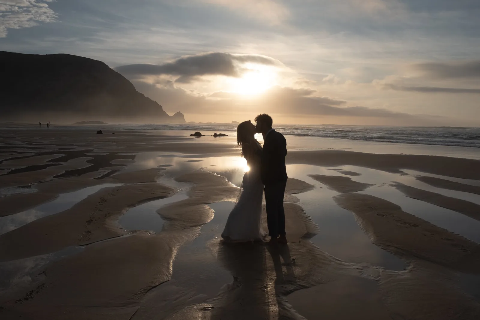 Ehepaar auf reflektierendem Strand bei Sonnenuntergang, Hochzeitsfotografie mit Licht