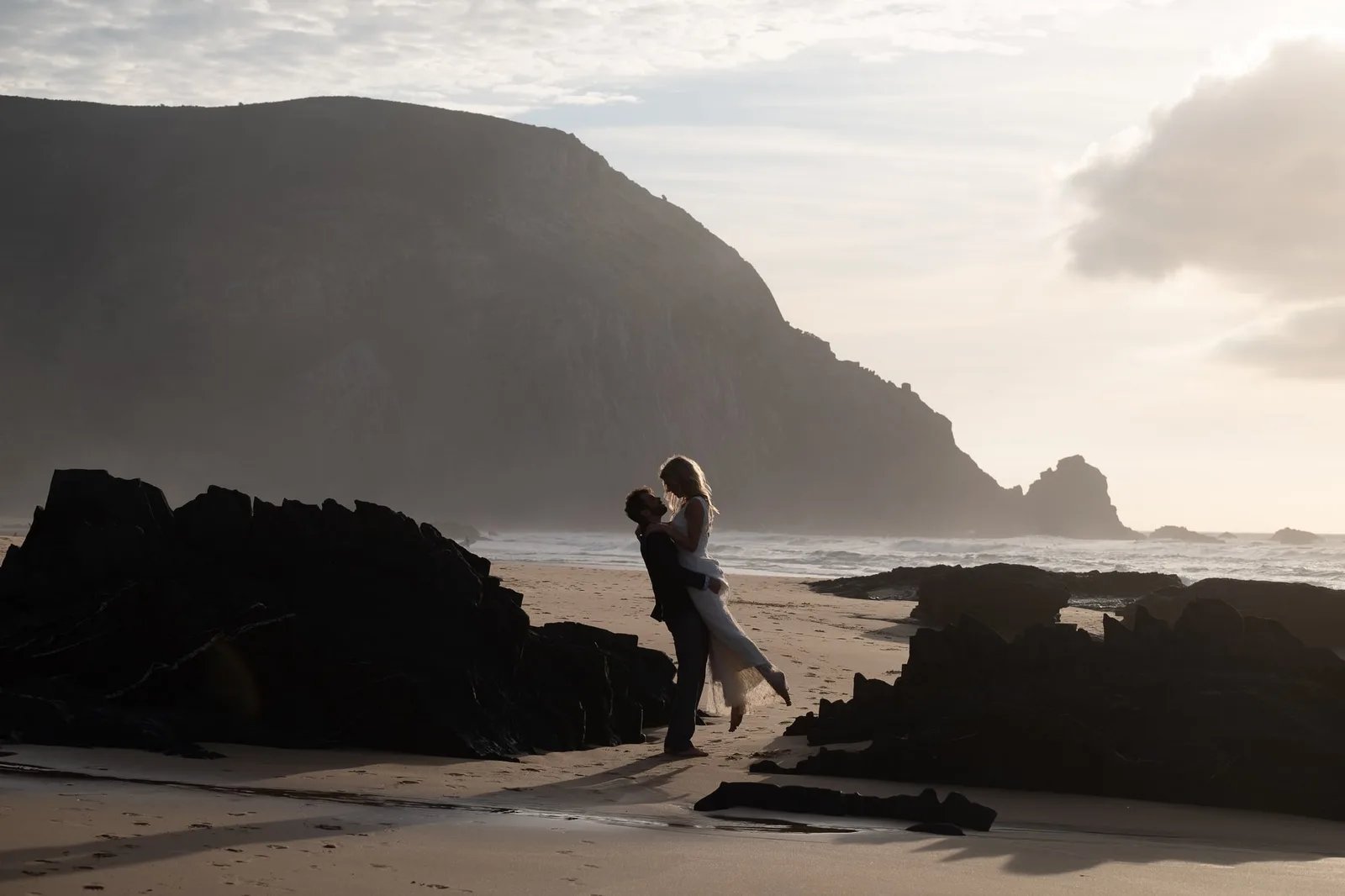 Ehepaar auf Felsen am Strand, dramatische Küstenlandschaft, Hochzeitsfotografie