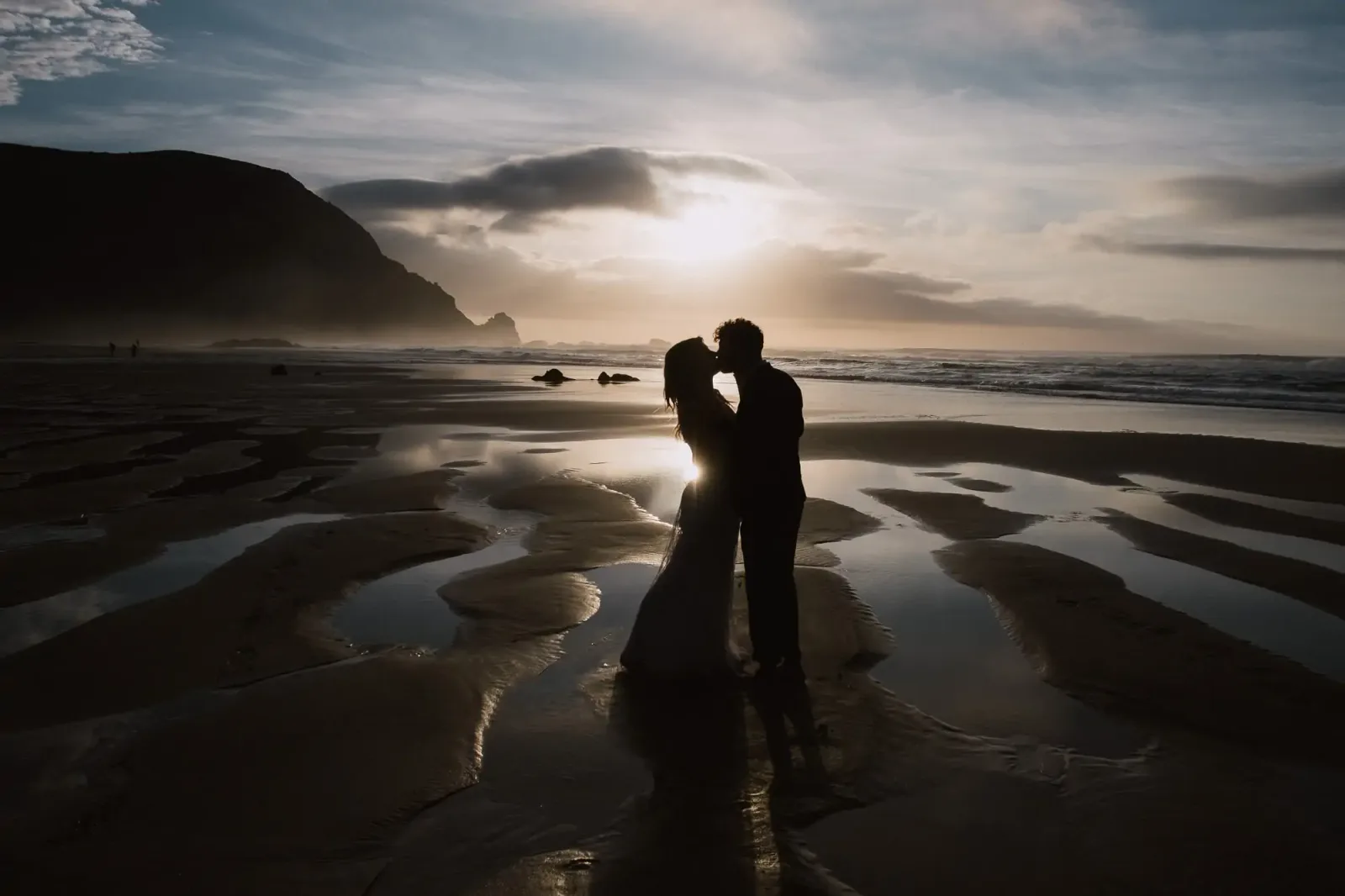 Brautpaar bei goldenem Licht auf Strand mit Meereshorizont, romantische Hochzeitsfotografie
