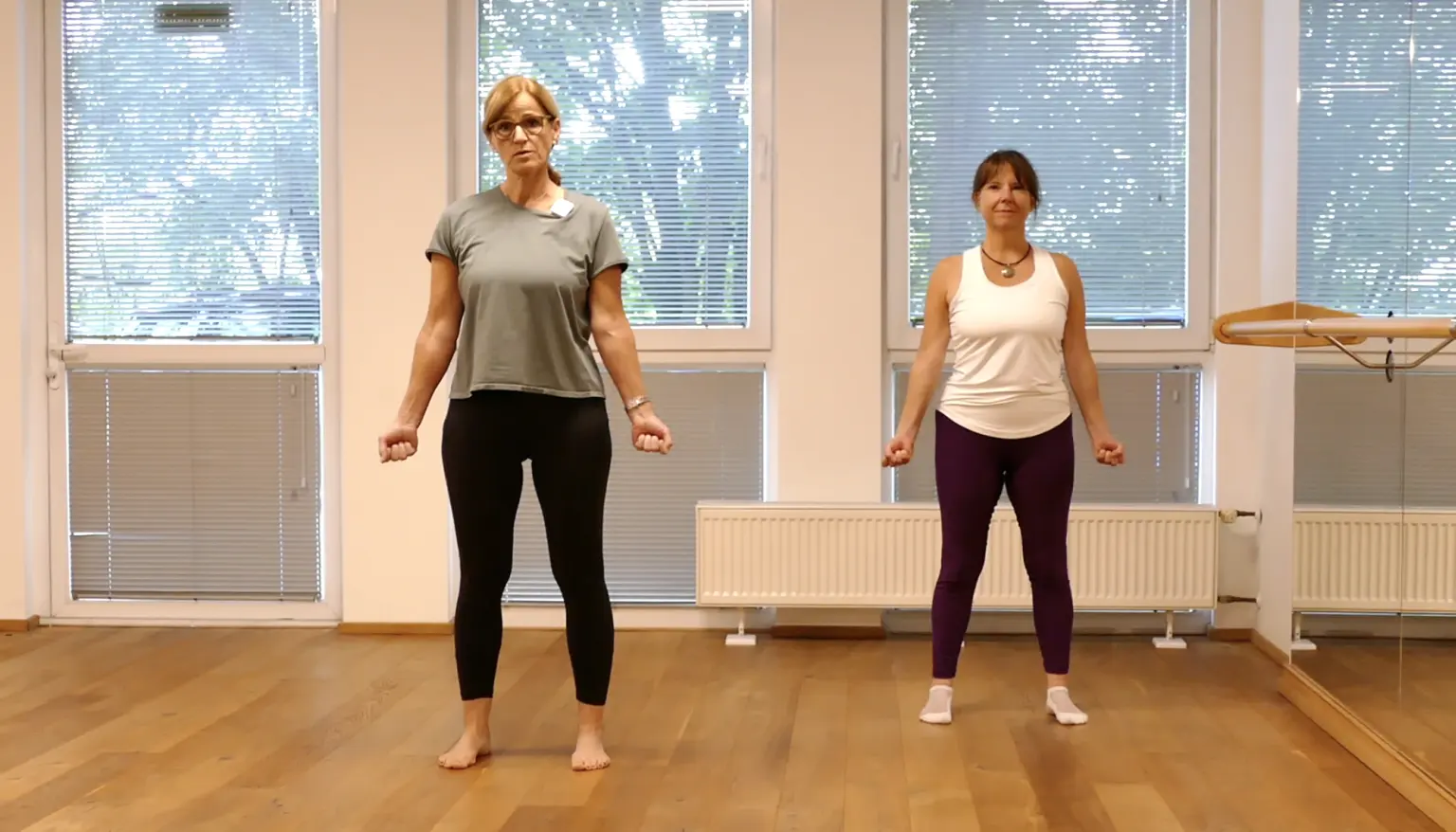 Zwei Frauen in Sportkleidung stehen sich in einem hellen Trainingsraum gegenüber