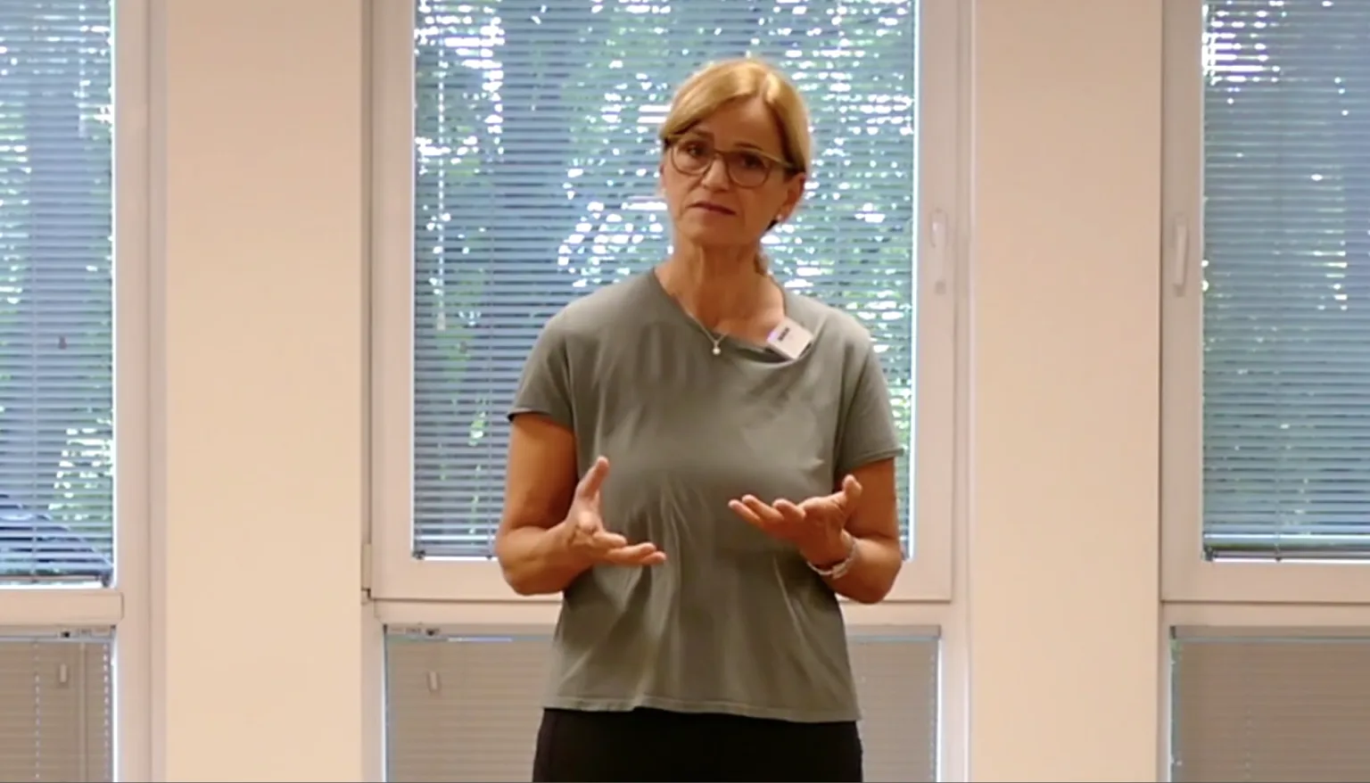 Kerstin Bredehorn in grauem T-Shirt mit Brille, frontal vor Fenster