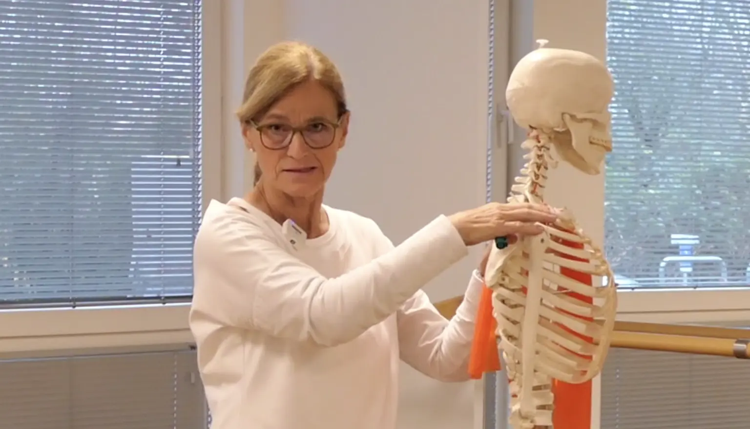 Autorin Kerstin Bredehorn zeigt Skelettmodell mit roten Bändern für Brustmuskulatur