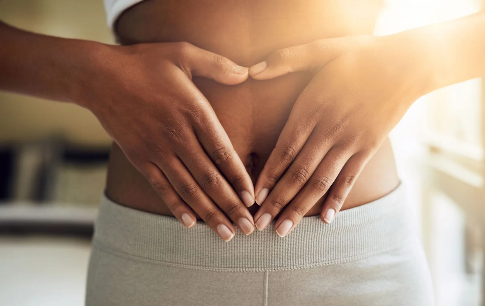 Frau hält Hände schützend über Bauch mit Symbolik für Hormongesundheit und Wohlbefinden