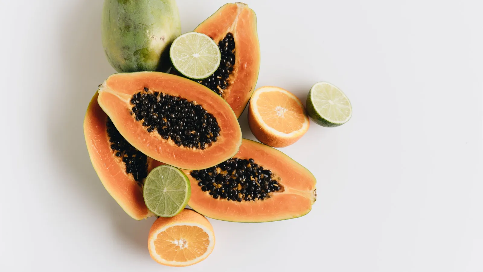 Papaya, Limetten und Orange auf weißem Hintergrund – detoxfreundliche Früchte und Lebensmittel