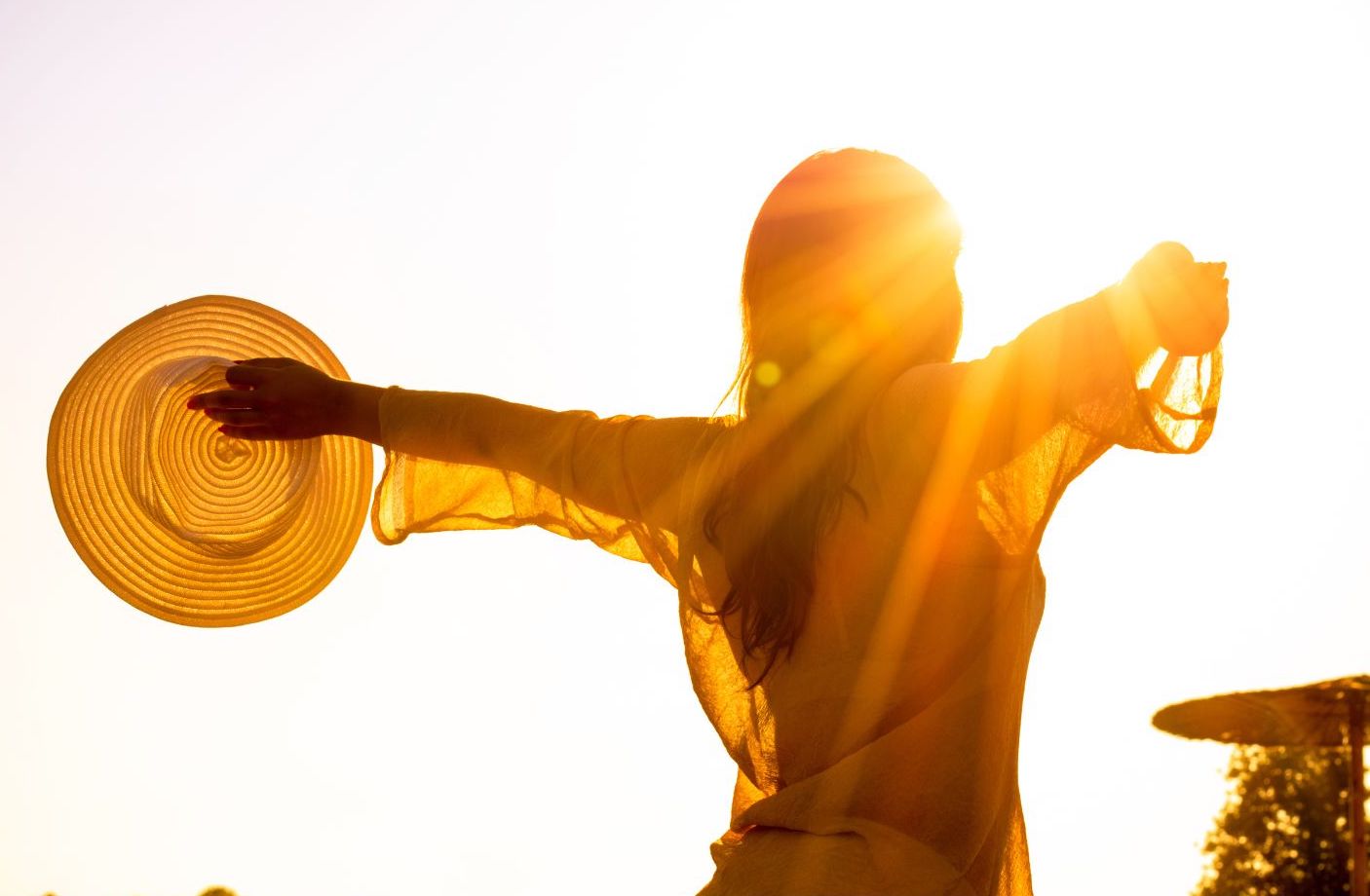 Silhouette einer Frau mit Strohhut in goldener Sonnenlicht-Atmosphäre symbolisiert Vitalität