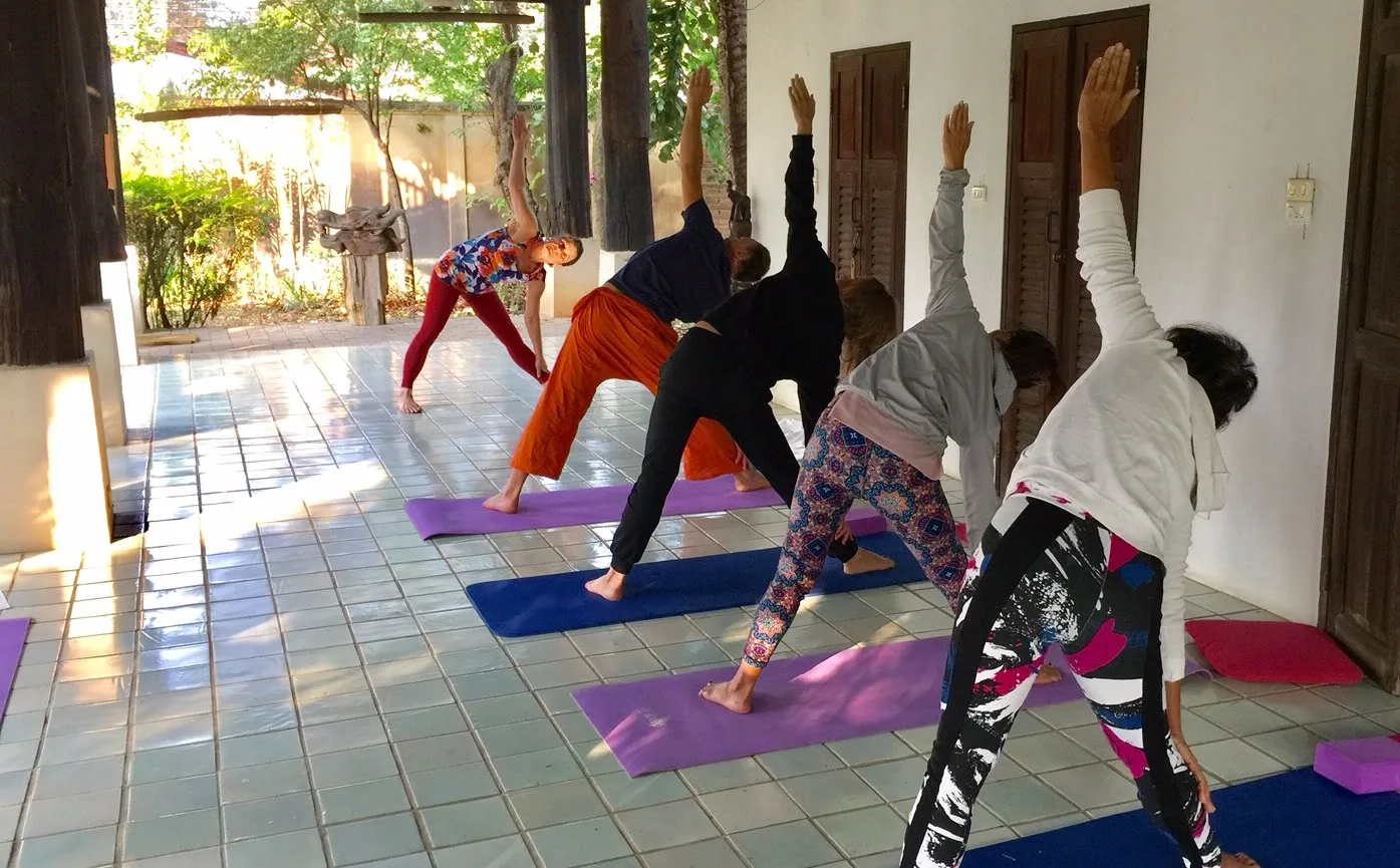 Gruppe von Frauen praktiziert Hormon-Yoga Posen auf farbigen Matten in Innenraum mit Sonnenlicht
