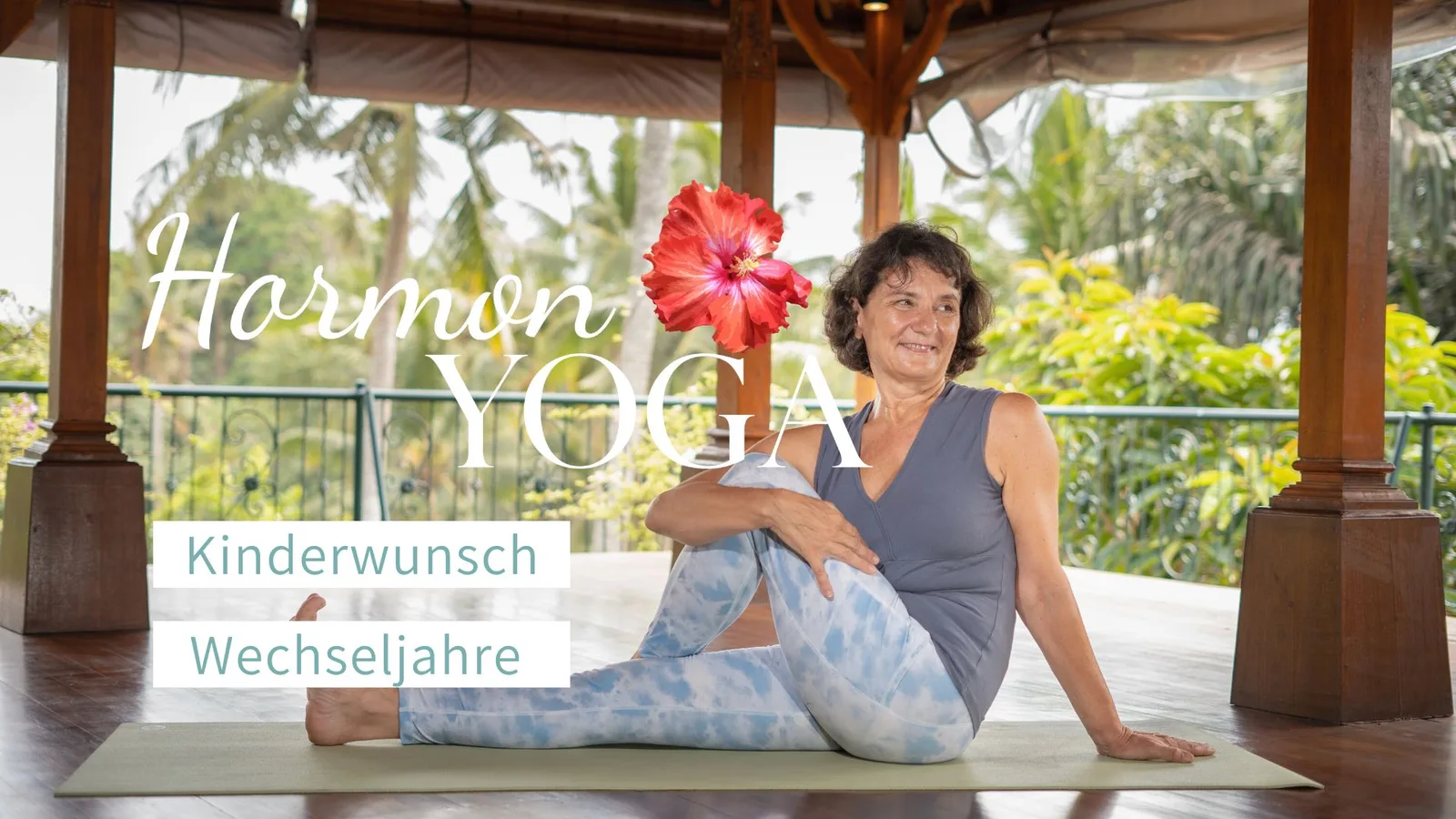 Frau in Yoga-Pose auf Matte unter tropischer Veranda mit roten Hibiskusblüten und Gartenblick