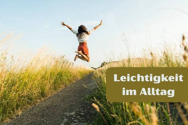 Frau springt freudig in die Luft auf Feldweg, umgeben von hohem Gras, mit Text-Overlay