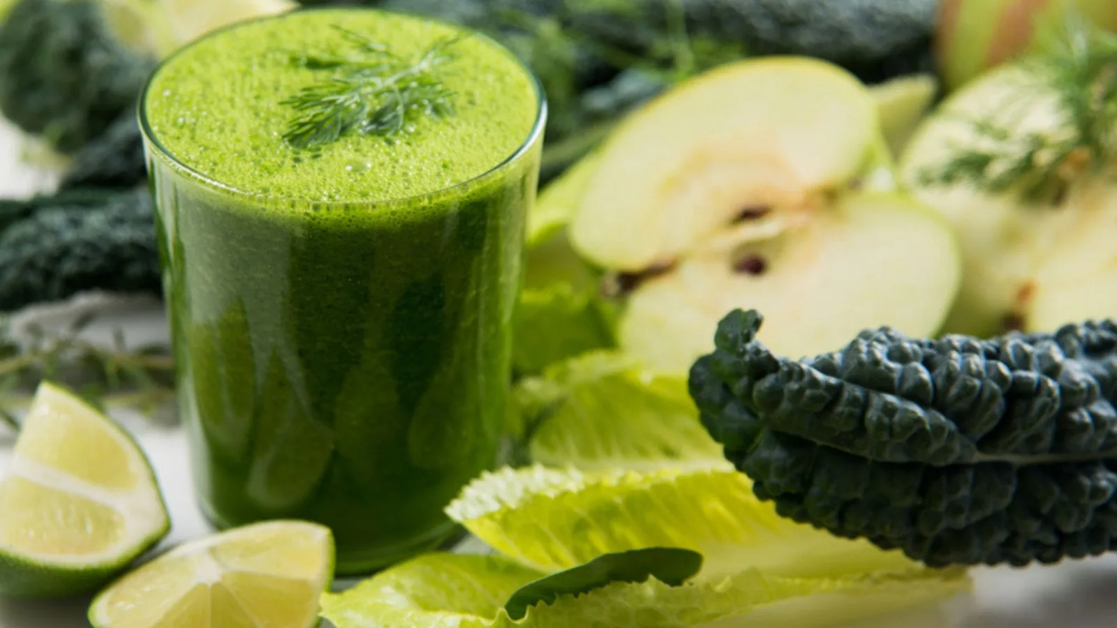 Grüner Detox-Smoothie mit frischem Gemüse, Limette und Kale auf weißem Untergrund