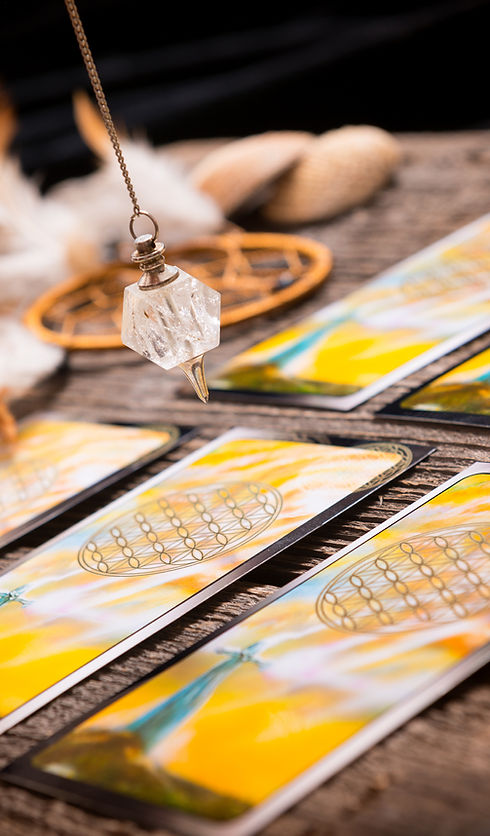Hypnosesitzung Special – Hypnose-Coaching bei Kränkungen 1 Wünschelrutenpendel aus Kristall über Tarotkarten, Steine und Holzuntergrund