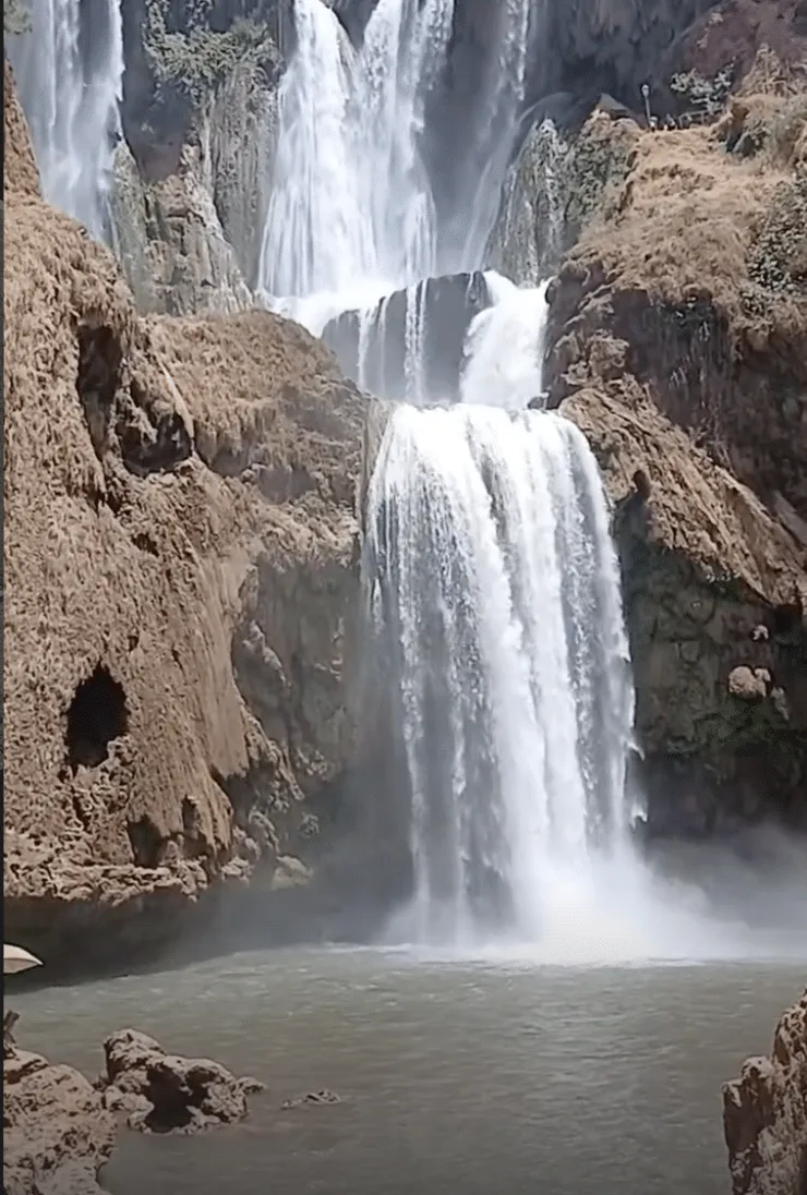 Gefrorener mehrstufiger Wasserfall zwischen braunen Felsklippen