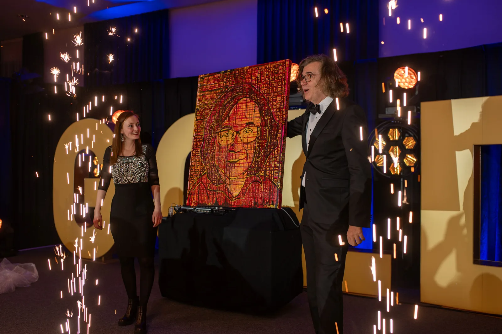 Maria Hennig und Hermann Scherer präsentieren rotes Kunstwerk auf beleuchteter Bühne