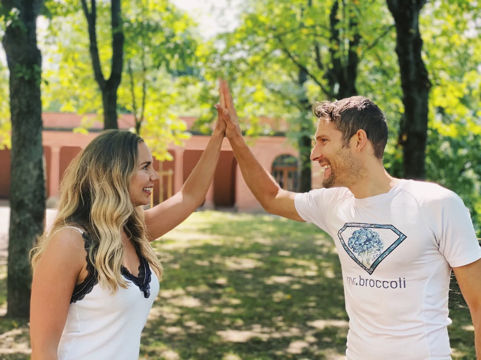 Mann und Frau High-Five im Park, beide in Mr. Broccoli Shirts