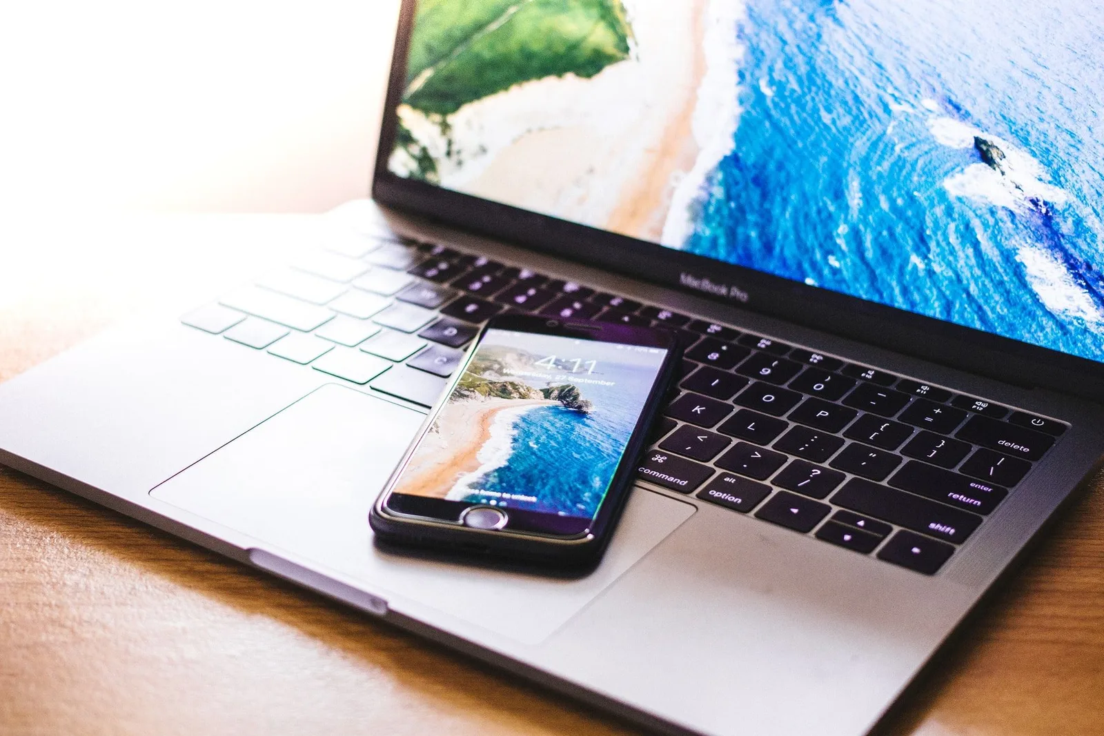 Smartphone und Laptop nebeneinander auf Holztisch mit Strand-Motiv