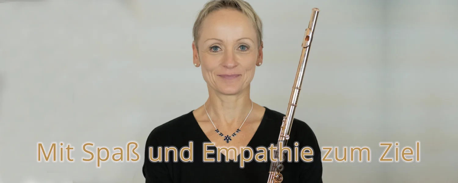 Flötenlehrer Katja Reinbold mit Flöte vor grauem Hintergrund, Text Mit Spaß und Empathie zum Ziel