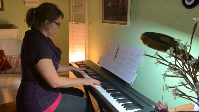 Schwangere Frau spielt Klavier mit Notenständer im Wohnzimmer