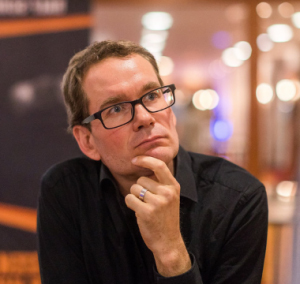 Porträt von Florian Schoel mit Brille im nachdenklichen Gesichtsausdruck