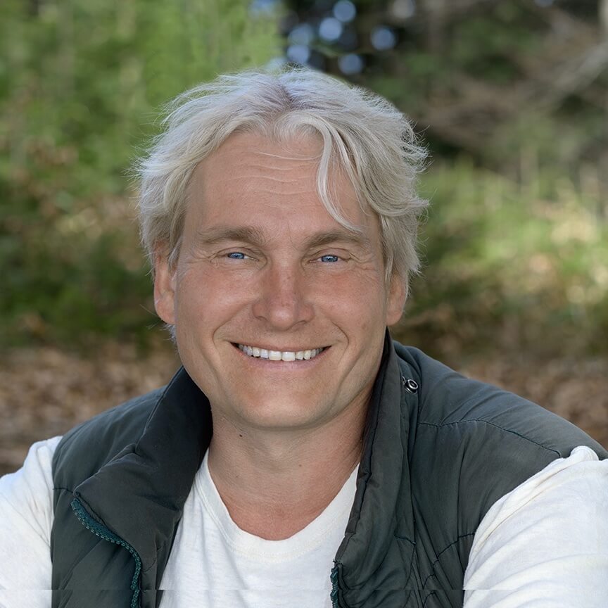 Porträtfoto von Uwe Albrecht, lächelnder Mann mit weißem Haar in schwarzer Weste
