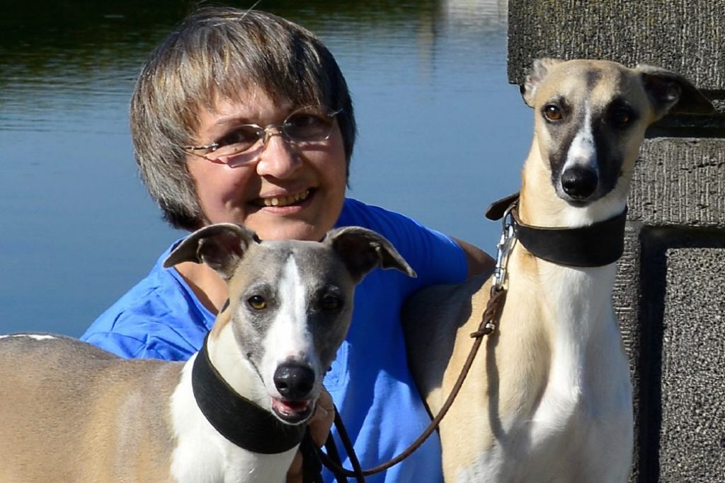 Eva Maria Krämer mit zwei braunen und weißen Whippets an der Leine, im Freien