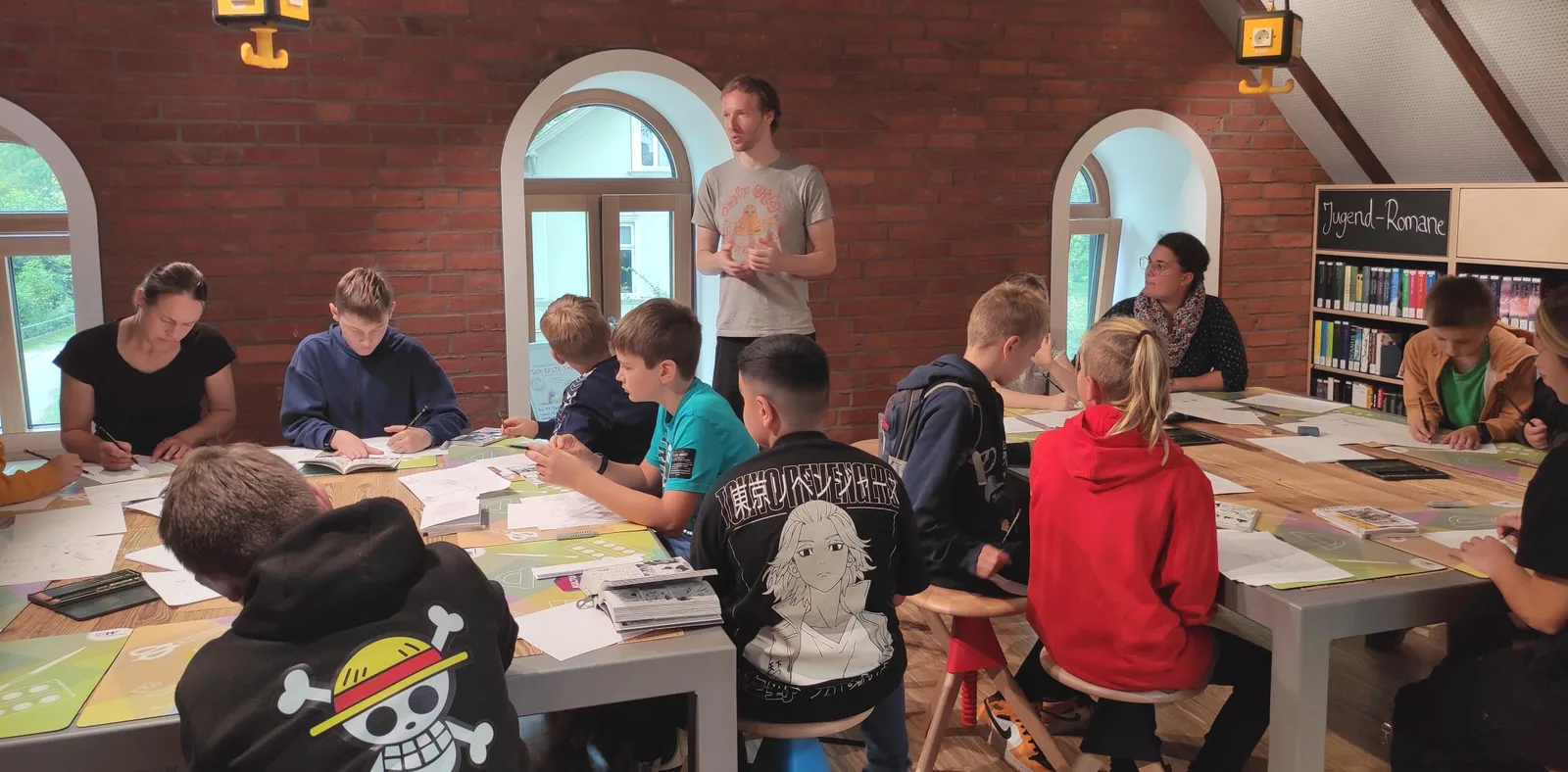 Maxim unterrichtet Kinder beim Manga-Zeichnen in einer Bibliothek