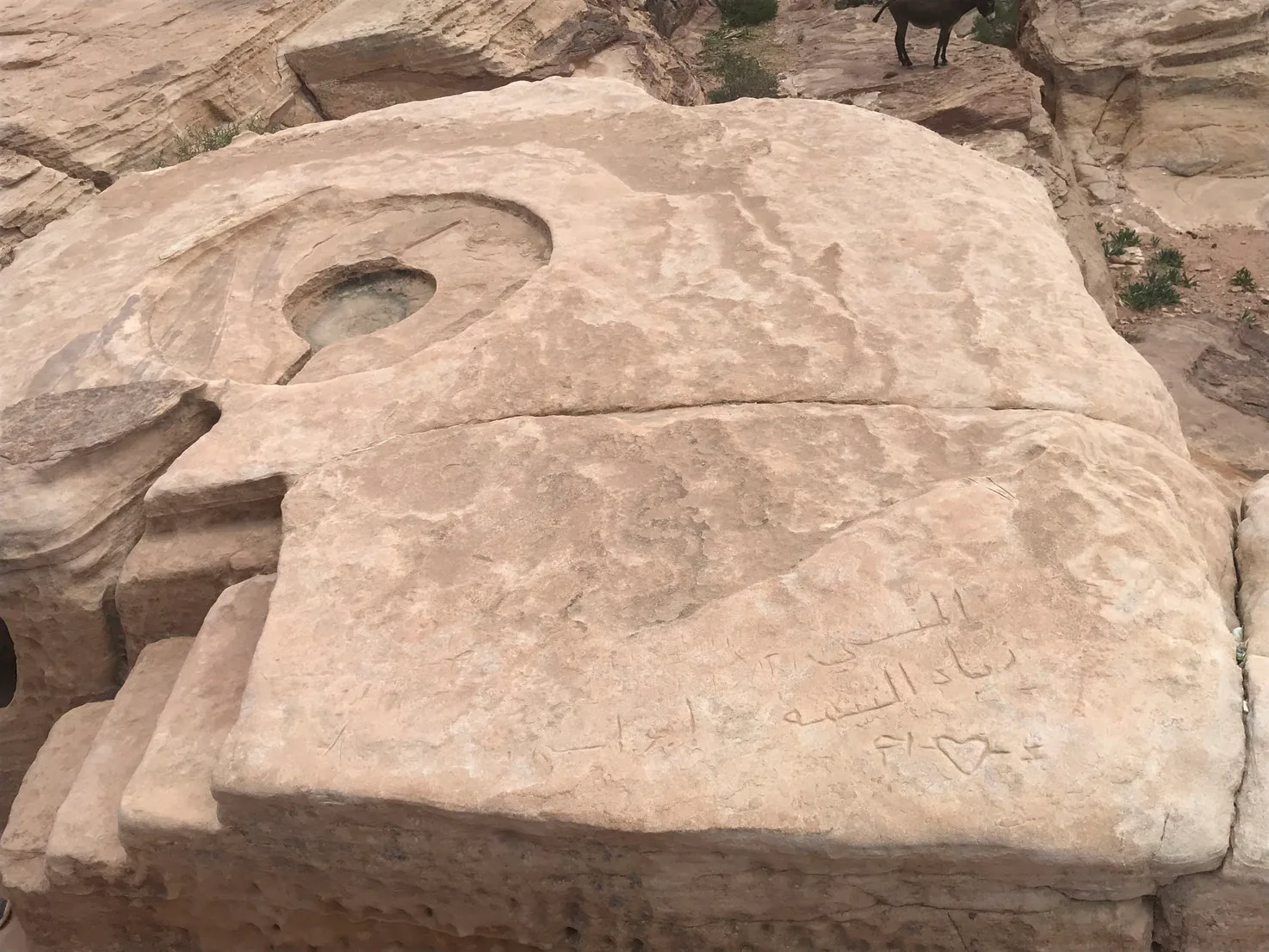 Steinrelief in Petra mit eingemeißelten Inschriften und Gesichtszügen