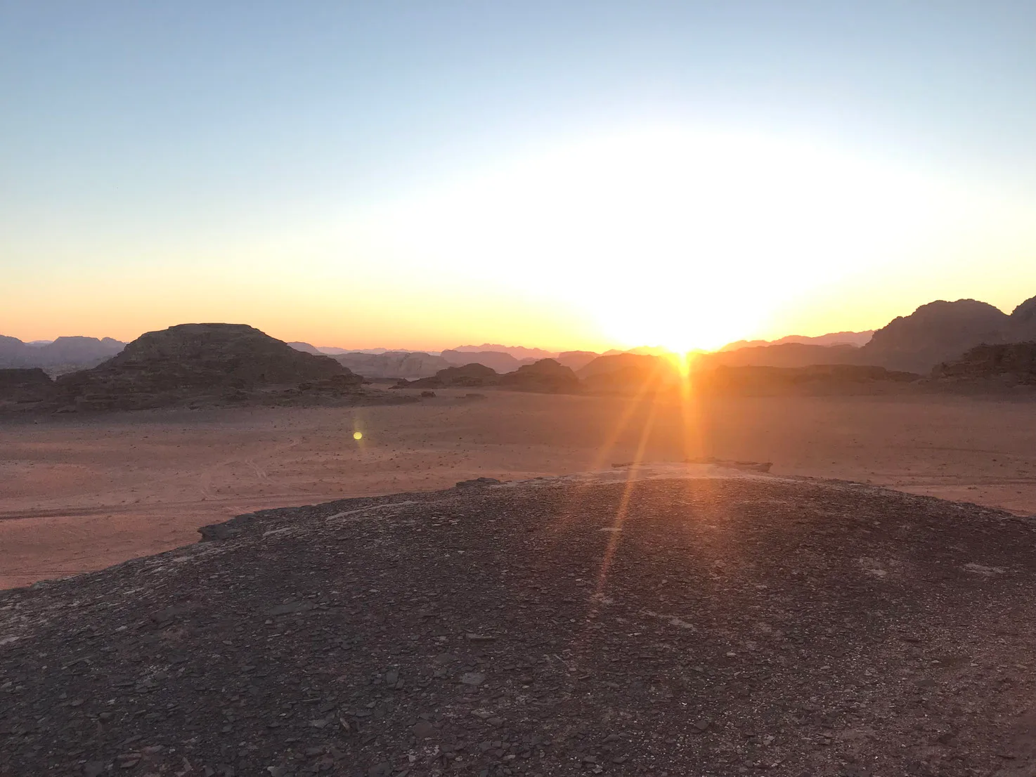 Wüstenlandschaft bei Sonnenaufgang mit Felsen und Bergen