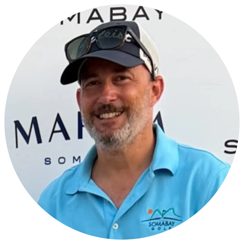Kaimana und die 12 Schlüssel – Coaching zur Selbsterkenntnis 10 Mann in hellblauem Poloshirt und Kappe mit Markenlogo im Hintergrund, lächelnd