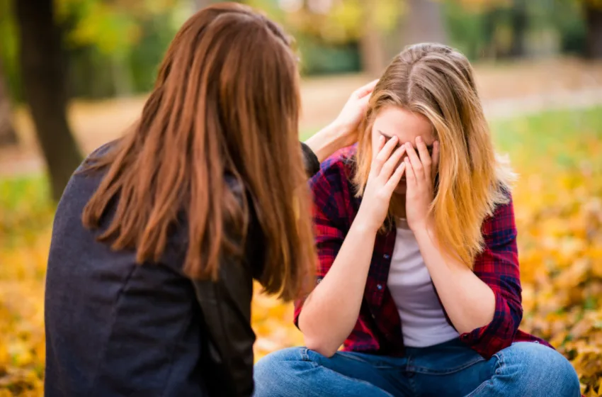 Zwei Frauen im Freien, eine tröstend die andere, Herbstlaub
