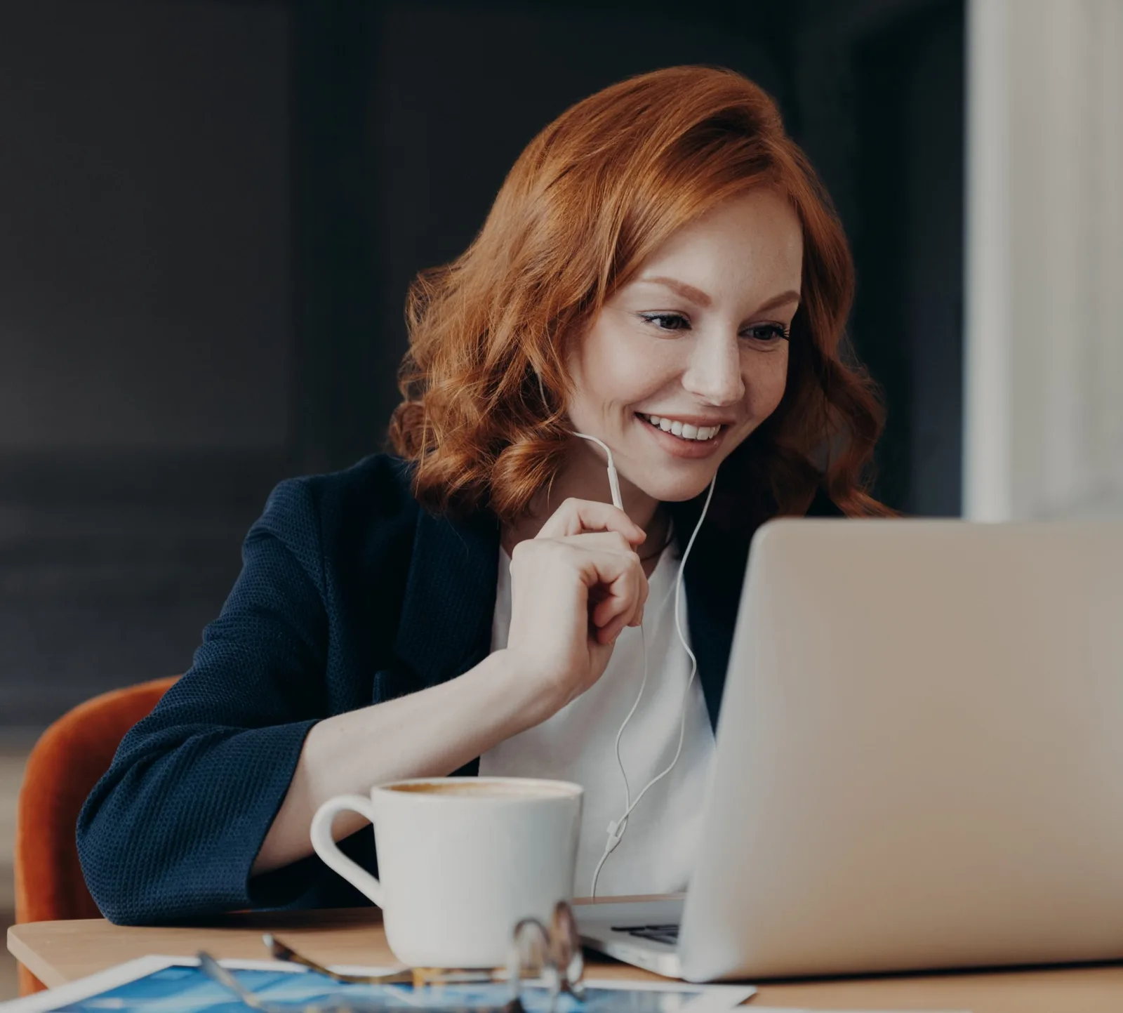 Frau mit roten Haaren am Laptop mit Kaffee, online Coaching