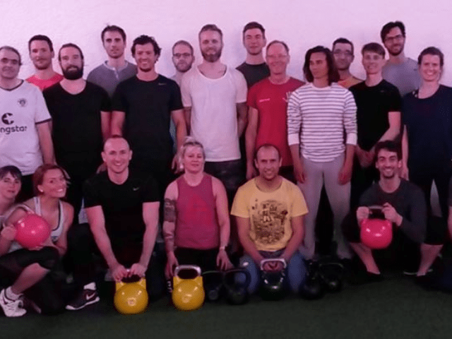Trainingsgruppe mit rosa und schwarzen Kettlebells auf lila Hintergrund