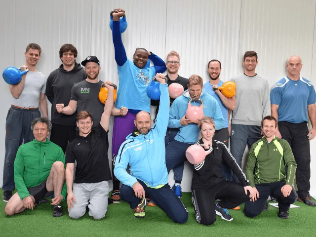 Sportgruppe mit Kettlebells und Hanteln in blauer Trainingsbekleidung