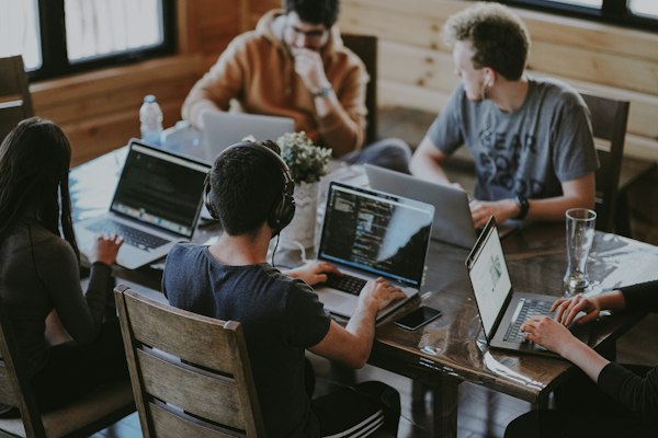 Team von vier Personen arbeitet gemeinsam an Laptops im Büro – Praxis Workshop Demo