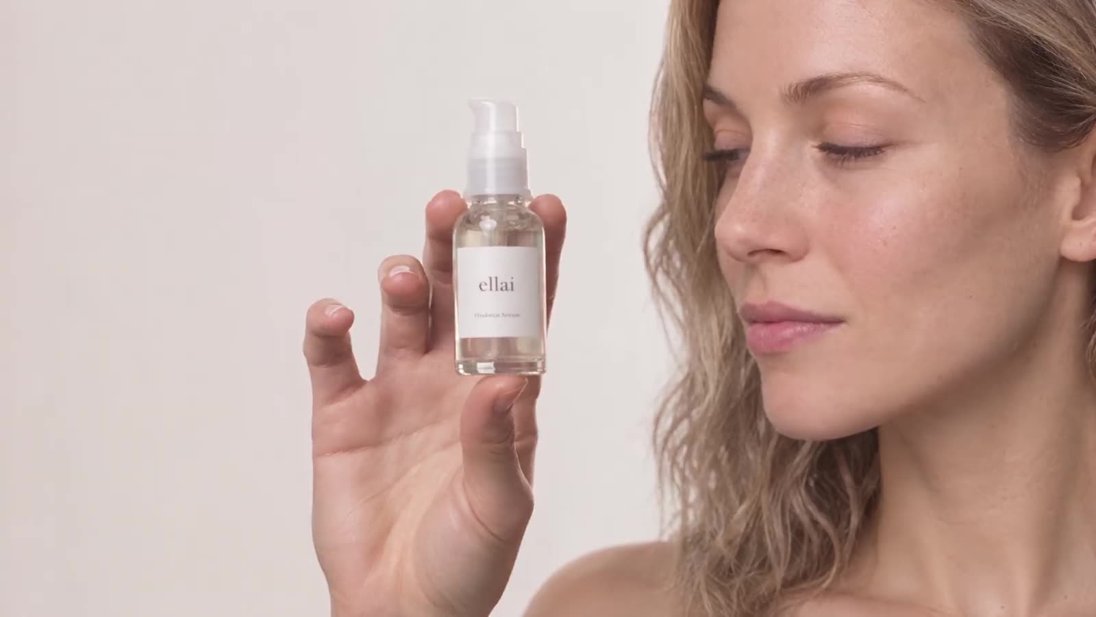 Frau präsentiert ellai Hautpflege-Spray vor hellem Hintergrund, Profil-Detailaufnahme