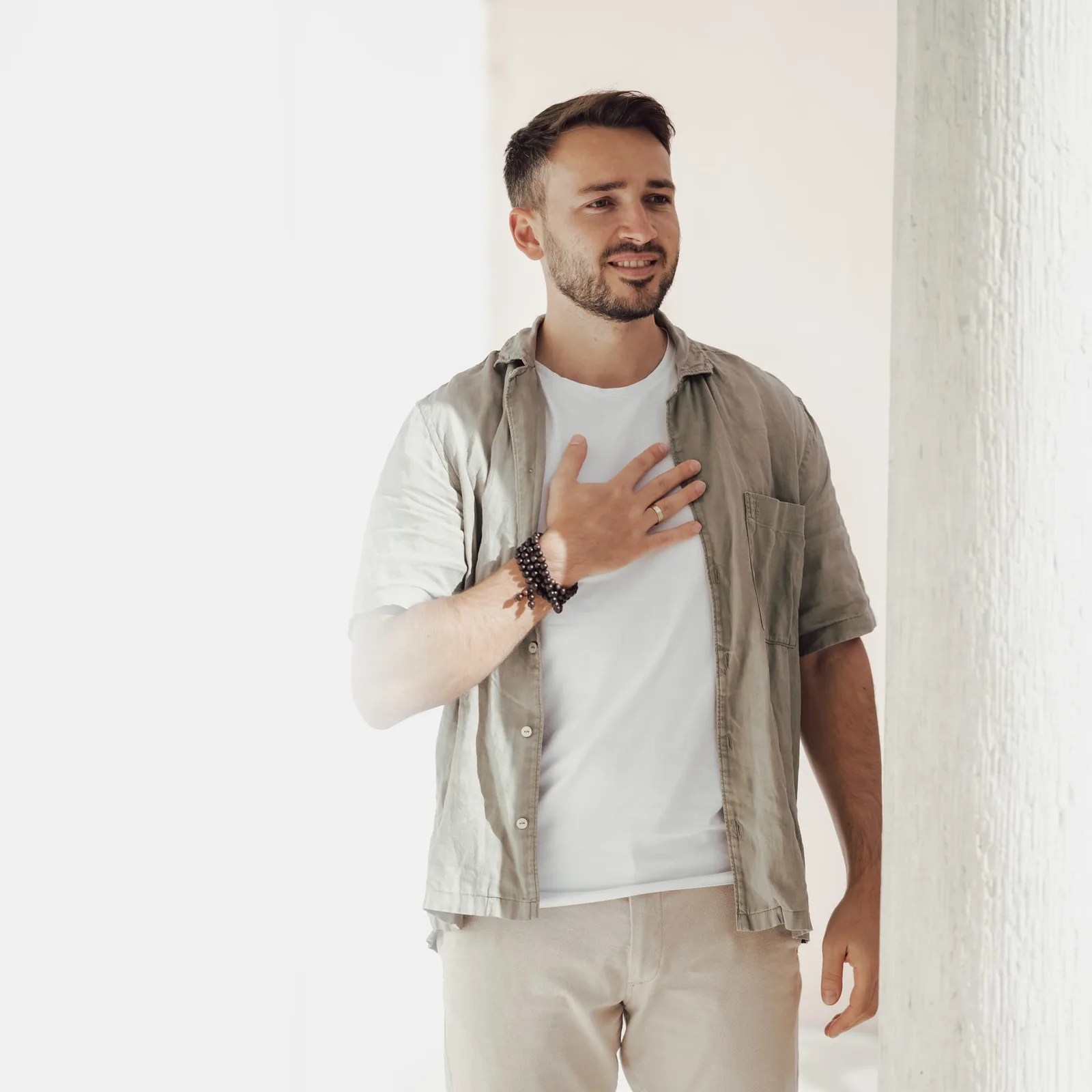 Junger Mann in Beige-Tönen mit schwarzem Kristallarmband am Handgelenk