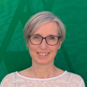 Ricarda Weitz, Frau mit grauer Brille und grauem Haar vor grünem Hintergrund